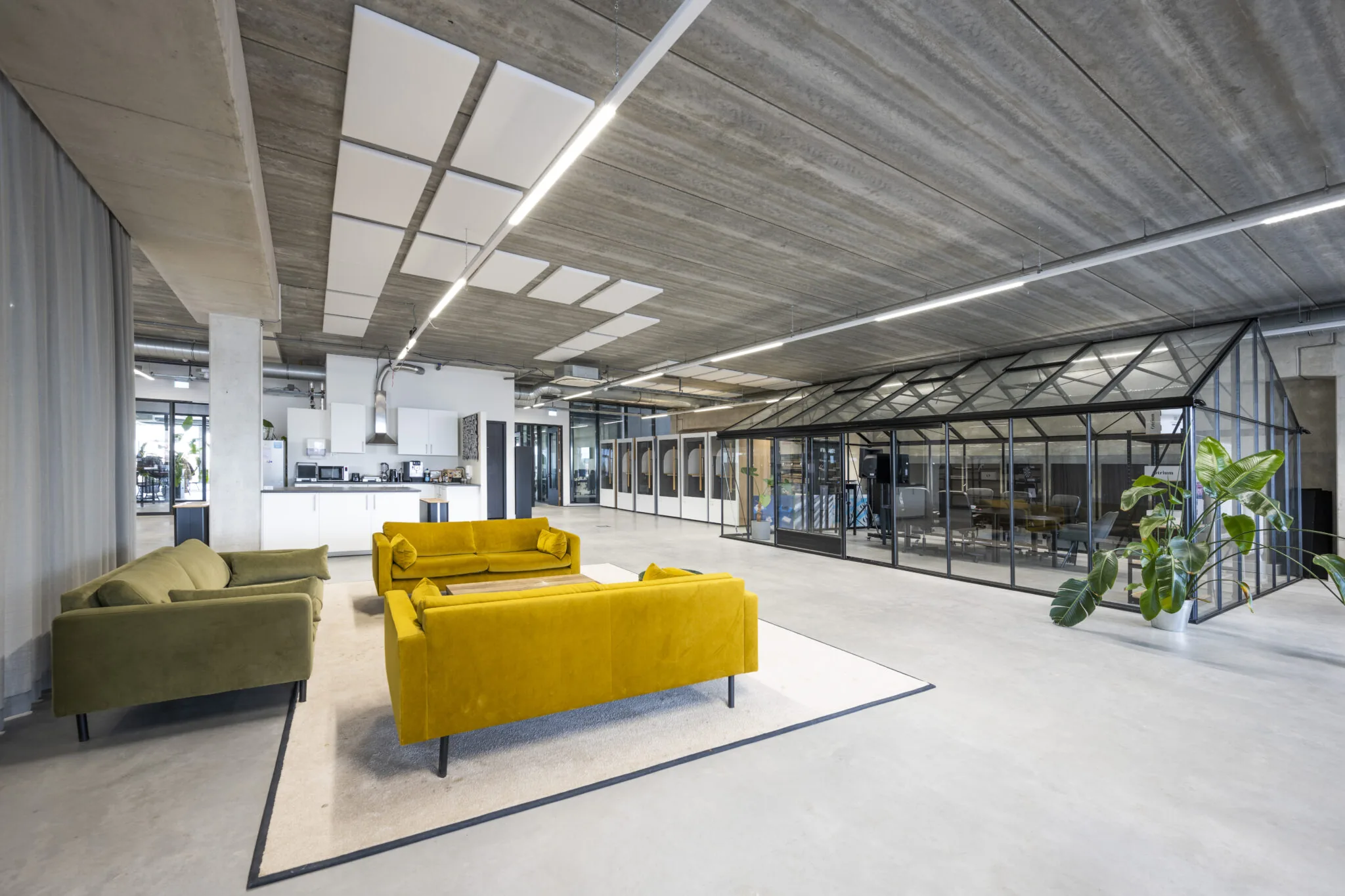 Moderne kantoorruimte aan de Danzigerkade met kleurrijke zitbanken, een glazen vergaderruimte en een open keuken.