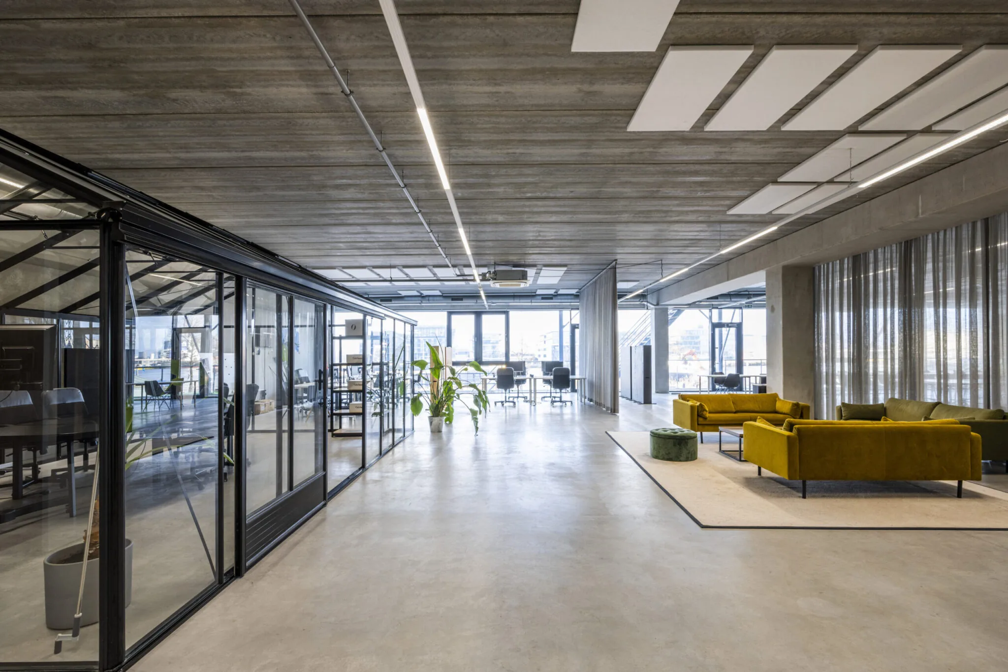 Moderne en ruime kantoorruimte aan de Danzigerkade 040, ontworpen door Paul Starink, met glazen vergaderruimtes en gele loungebanken.