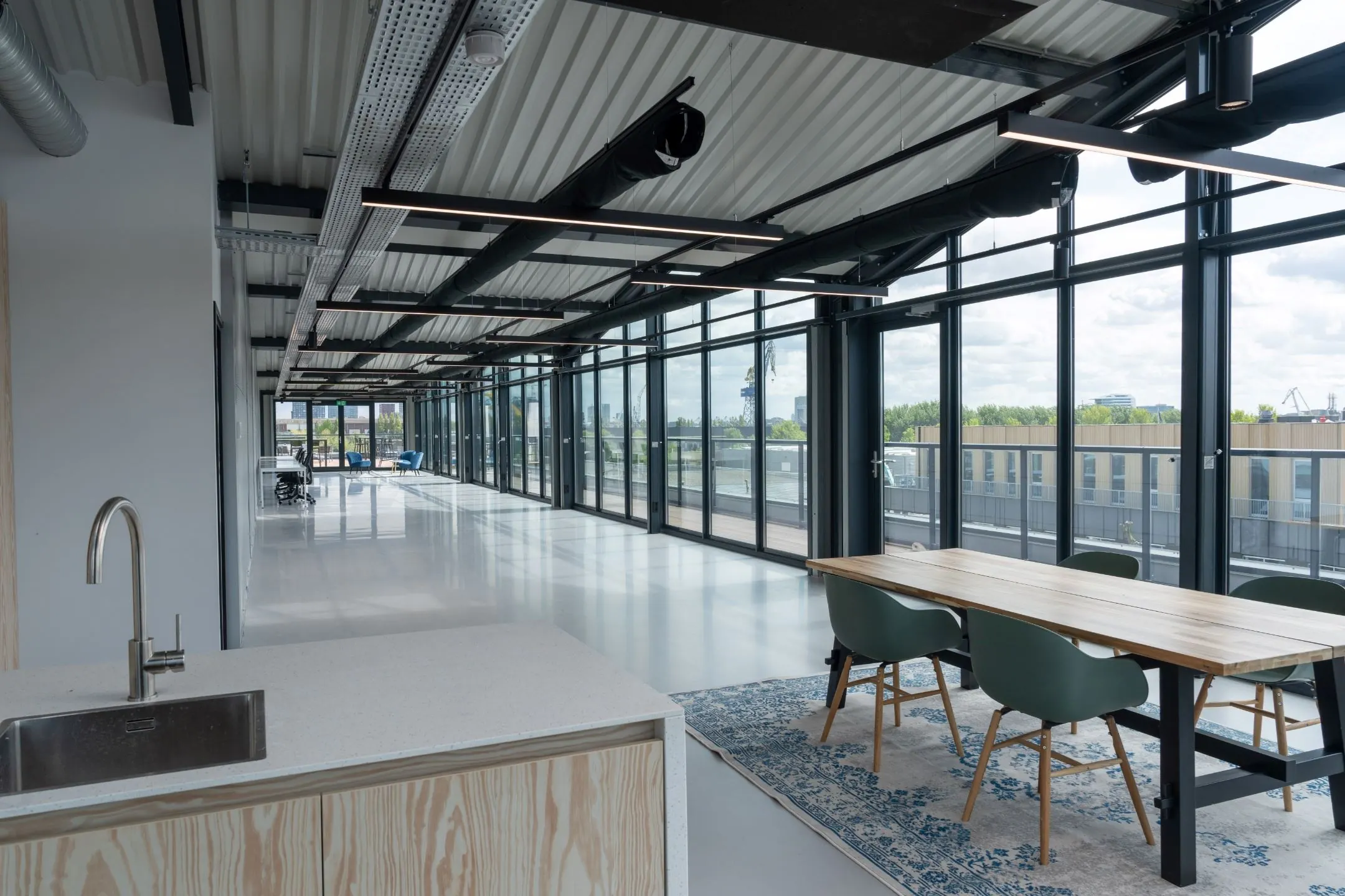 Moderne, open kantoorruimte aan de Disketteweg 14 met grote ramen, vergadertafel en kitchenette.