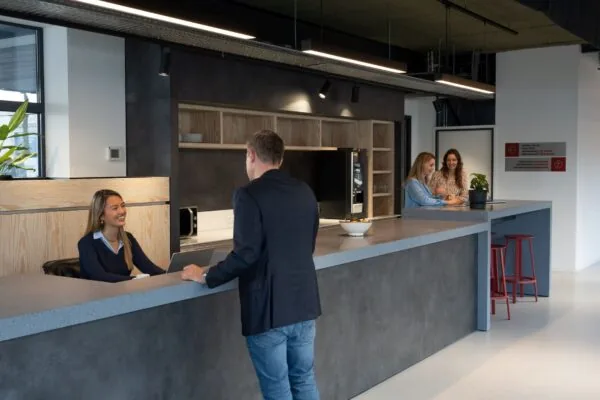 Receptiebalie en moderne pantry in een kantoor aan de Disketteweg 14 met medewerkers in gesprek.