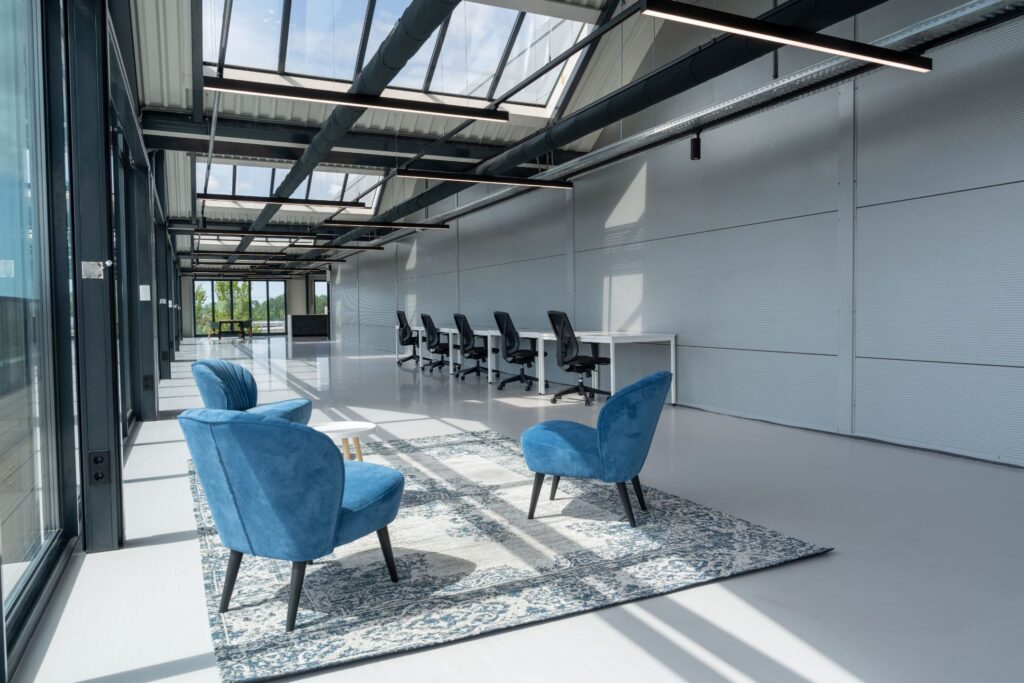 Moderne kantoorruimte aan de Disketteweg 14 met een open indeling, blauwe loungefauteuils en werkplekken langs de wand.