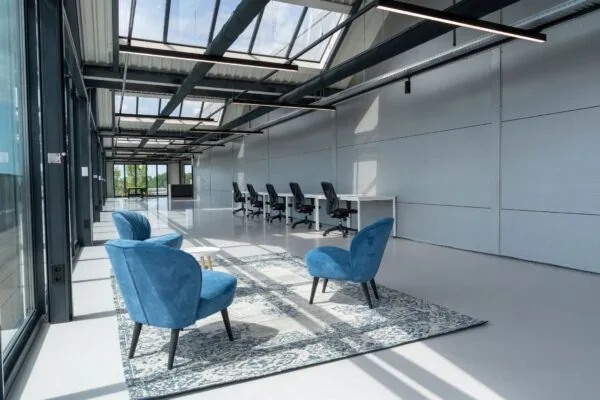 Moderne kantoorruimte aan de Disketteweg 14 met een open indeling, blauwe loungefauteuils en werkplekken langs de wand.