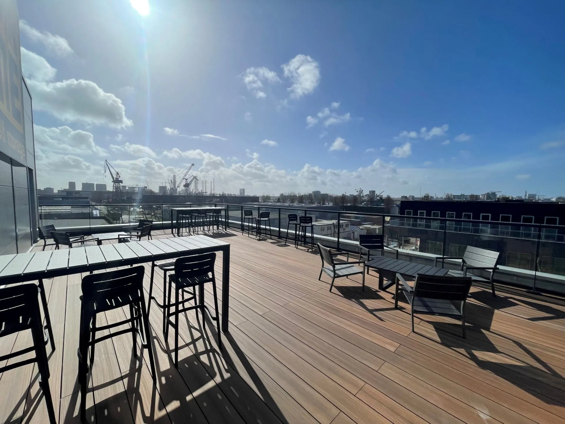 Zonnig dakterras met houten vloer en zitgelegenheid op Disketteweg 14, met uitzicht op havenkranen en industrieterrein.