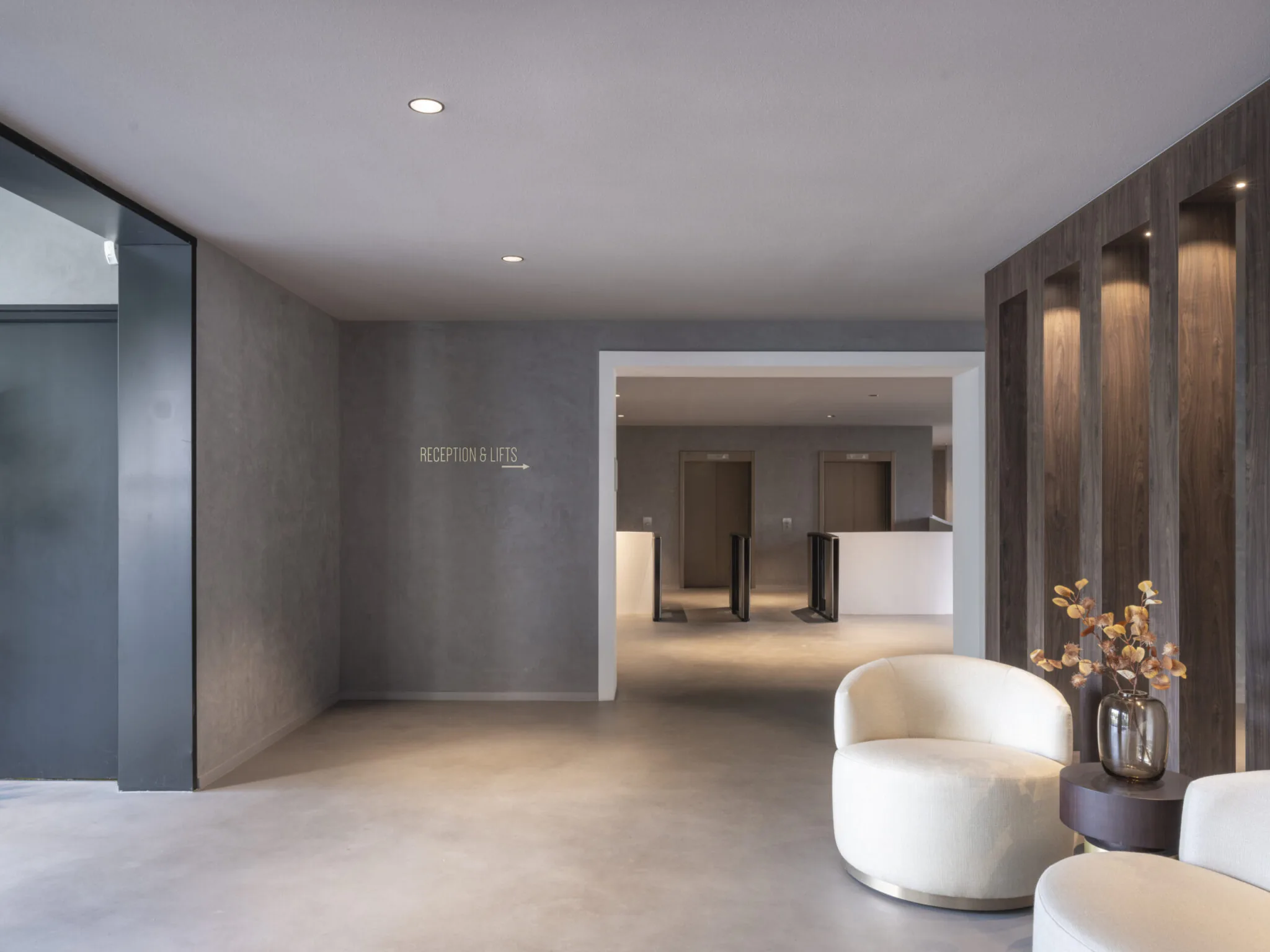 Moderne ontvangsthal van Element Offices in Tower 42 met stijlvolle zitstoelen, houten accenten en zicht op de liften en toegangspoortjes.