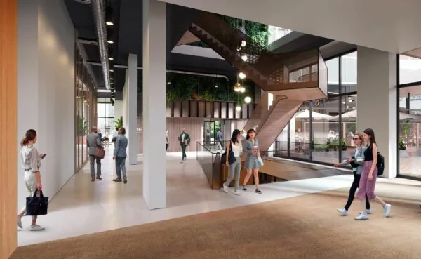 Moderne entreehal van een kantoorgebouw met een trap, veel daglicht en mensen die zich verplaatsen of met elkaar praten.