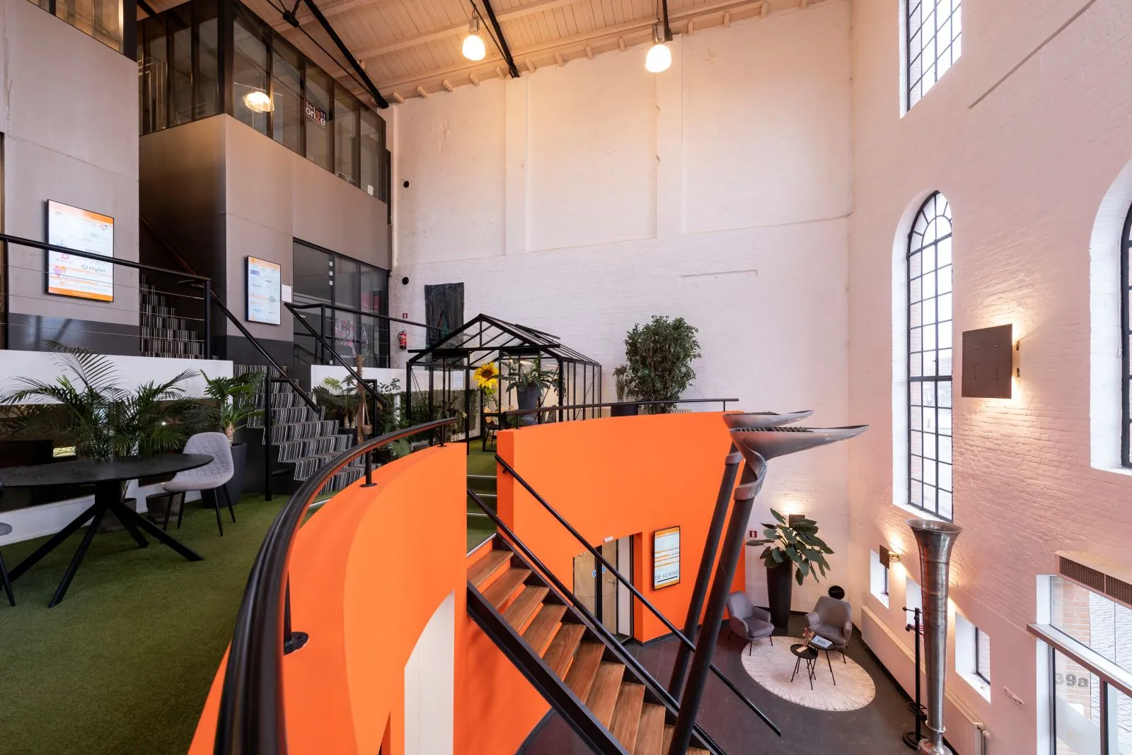 Moderne kantoorruimte genaamd entresol Suiker-4 met een opvallende oranje trap, glazen vergaderruimte en hoge ramen.