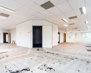Leegstaand kantoorpand van Hanzevast met opengewerkte ruimtes, systeemplafond en verwijderde vloerbedekking.