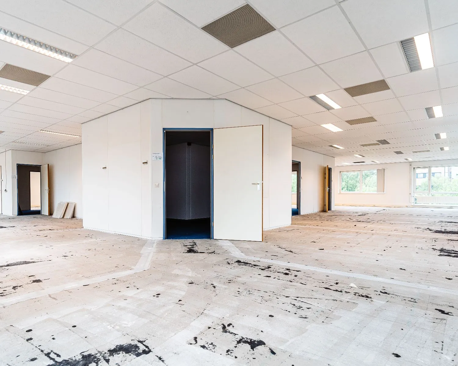 Leegstaand kantoorpand van Hanzevast met opengewerkte ruimtes, systeemplafond en verwijderde vloerbedekking.