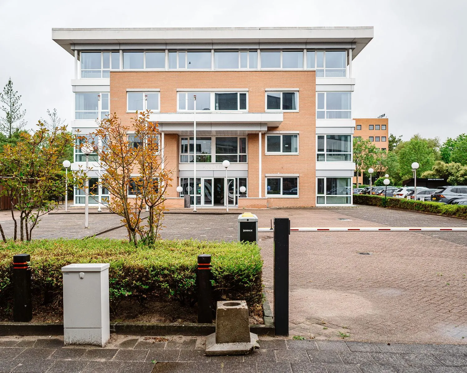 Vooraanzicht van een modern kantoorpand van Hanzevast met parkeerterrein en slagboom.