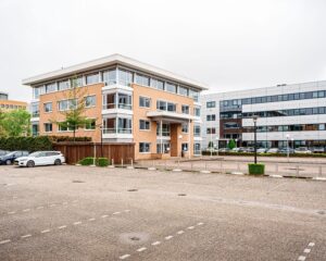 Kantoorgebouw van Hanzevast met parkeergelegenheid op de voorgrond.