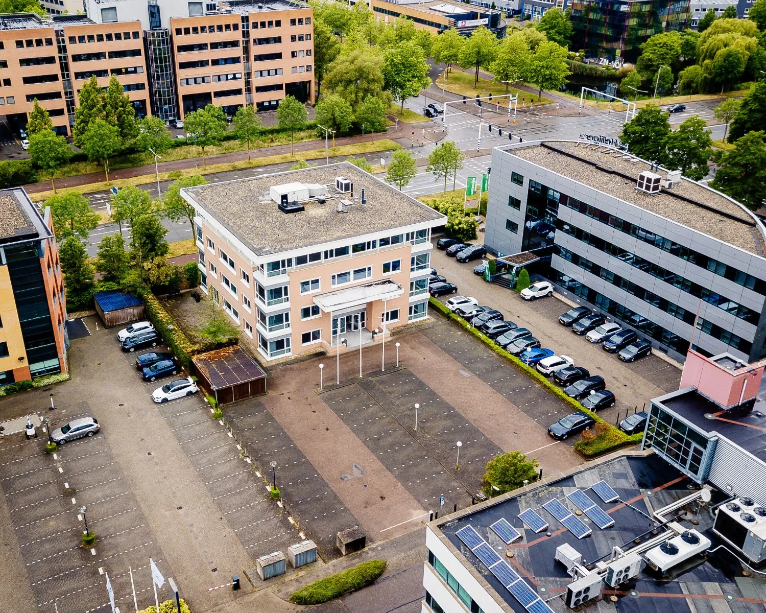 Luchtfoto van een kantoorgebouw van Hanzevast met omliggende parkeerplaatsen en omliggende kantoren.