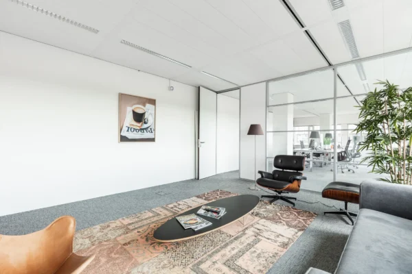 Moderne wachtruimte op Herengracht 204 met designmeubilair, een vloerkleed en een kunstwerk aan de muur.
