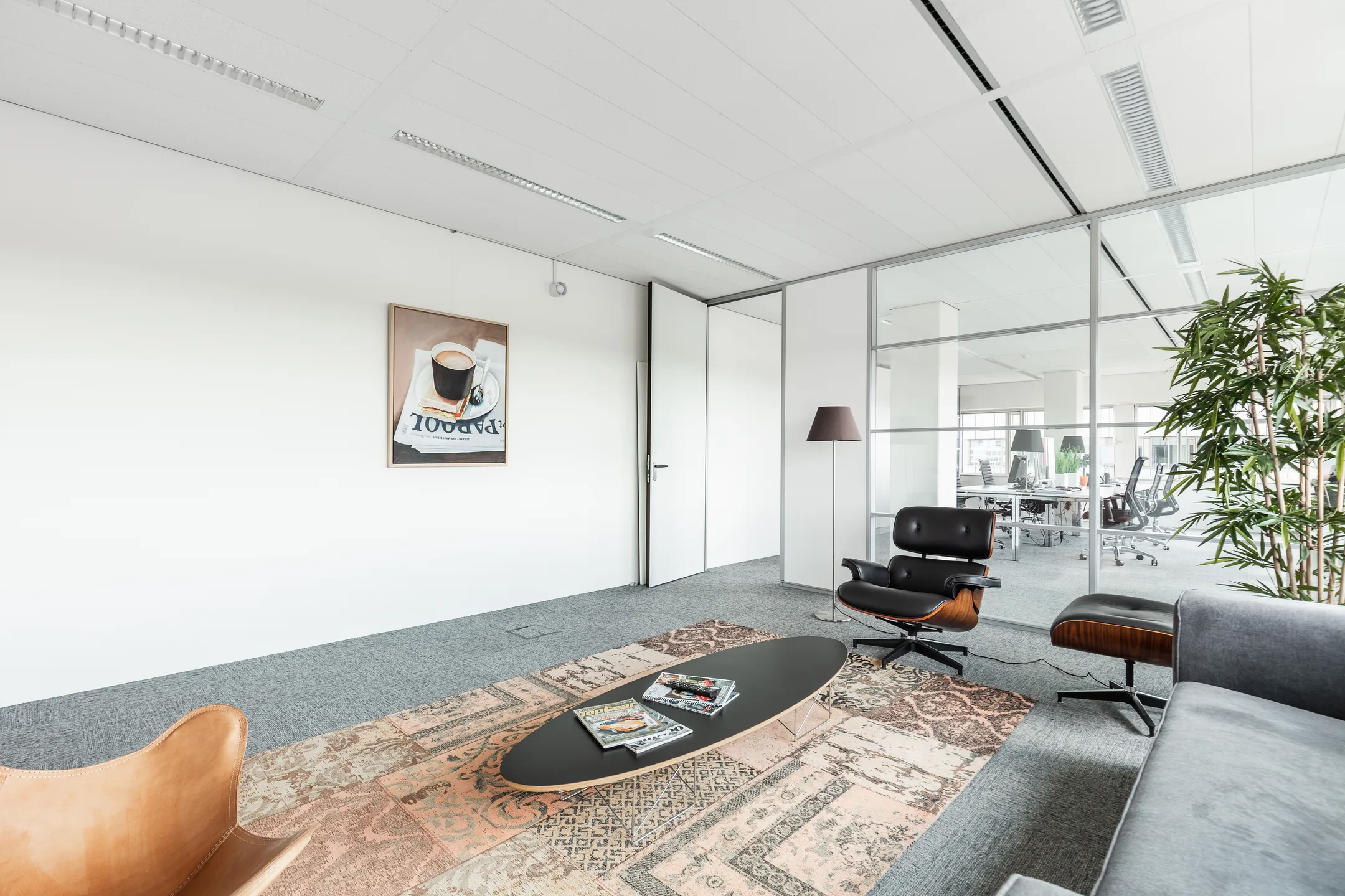 Moderne wachtruimte op Herengracht 204 met designmeubilair, een vloerkleed en een kunstwerk aan de muur.