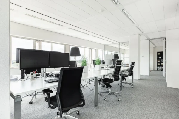 Modern en licht kantoorinterieur op Herengracht 204 met bureaus, bureaustoelen en computerschermen.