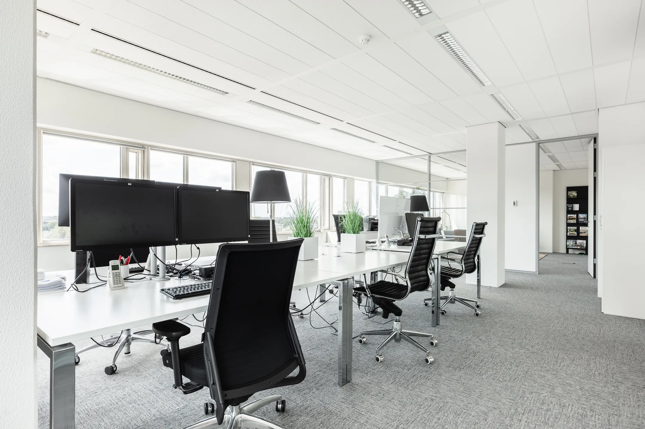Modern en licht kantoorinterieur op Herengracht 204 met bureaus, bureaustoelen en computerschermen.