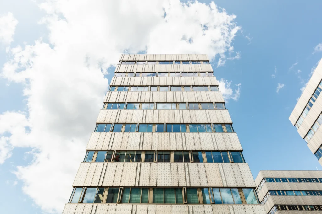 Voorgevel van het moderne kantoorgebouw aan Herengracht 204, gezien vanaf de straat tegen een blauwe lucht.