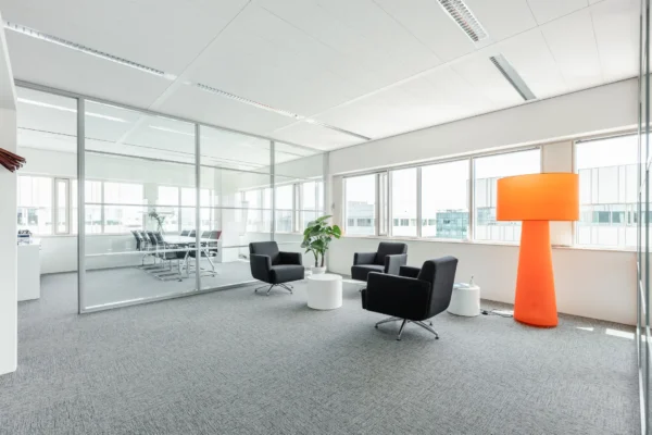 Moderne kantoorruimte op Herengracht 204 met zithoek, vergaderruimte en opvallende oranje vloerlamp.