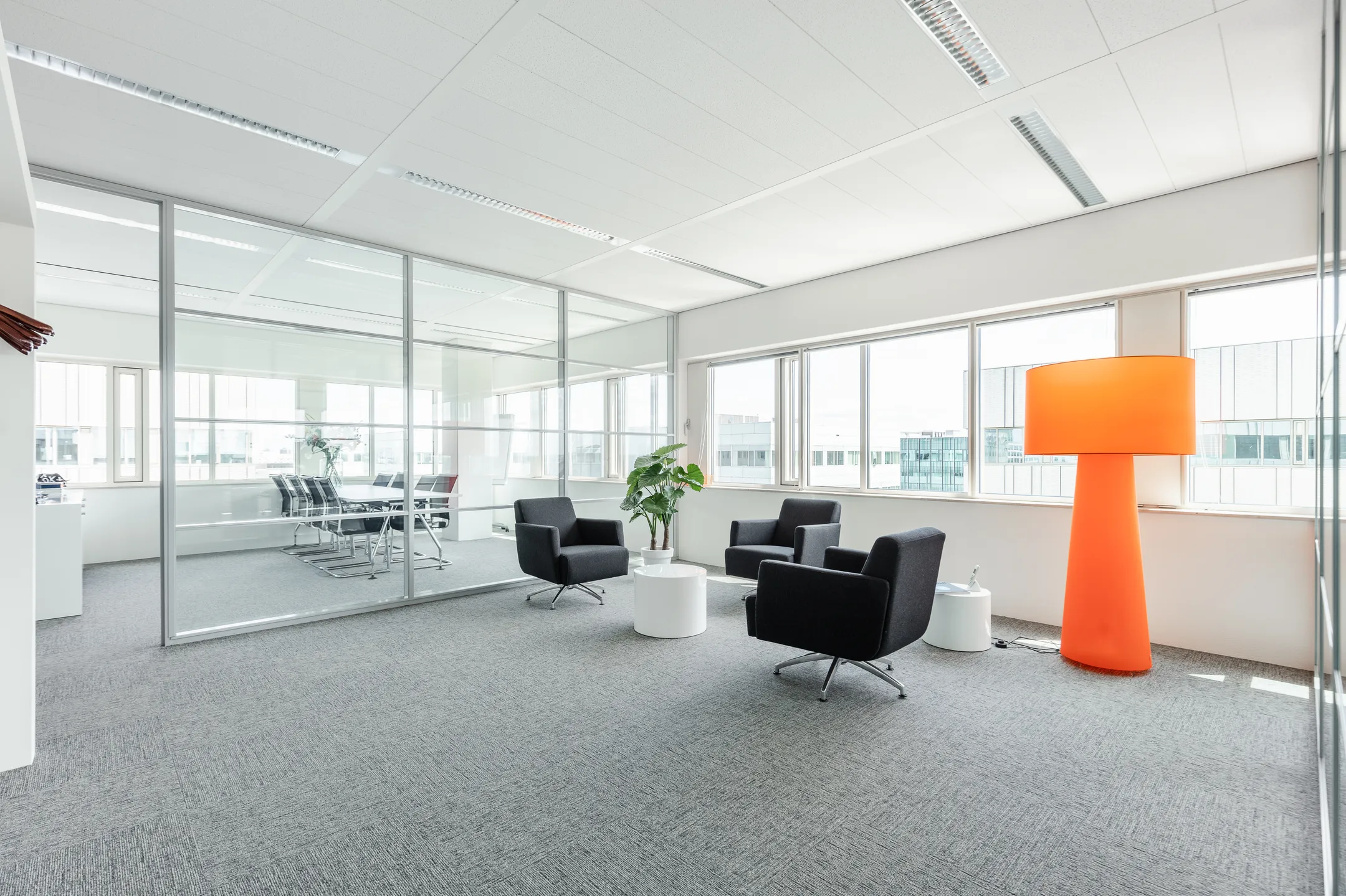Moderne kantoorruimte op Herengracht 204 met zithoek, vergaderruimte en opvallende oranje vloerlamp.