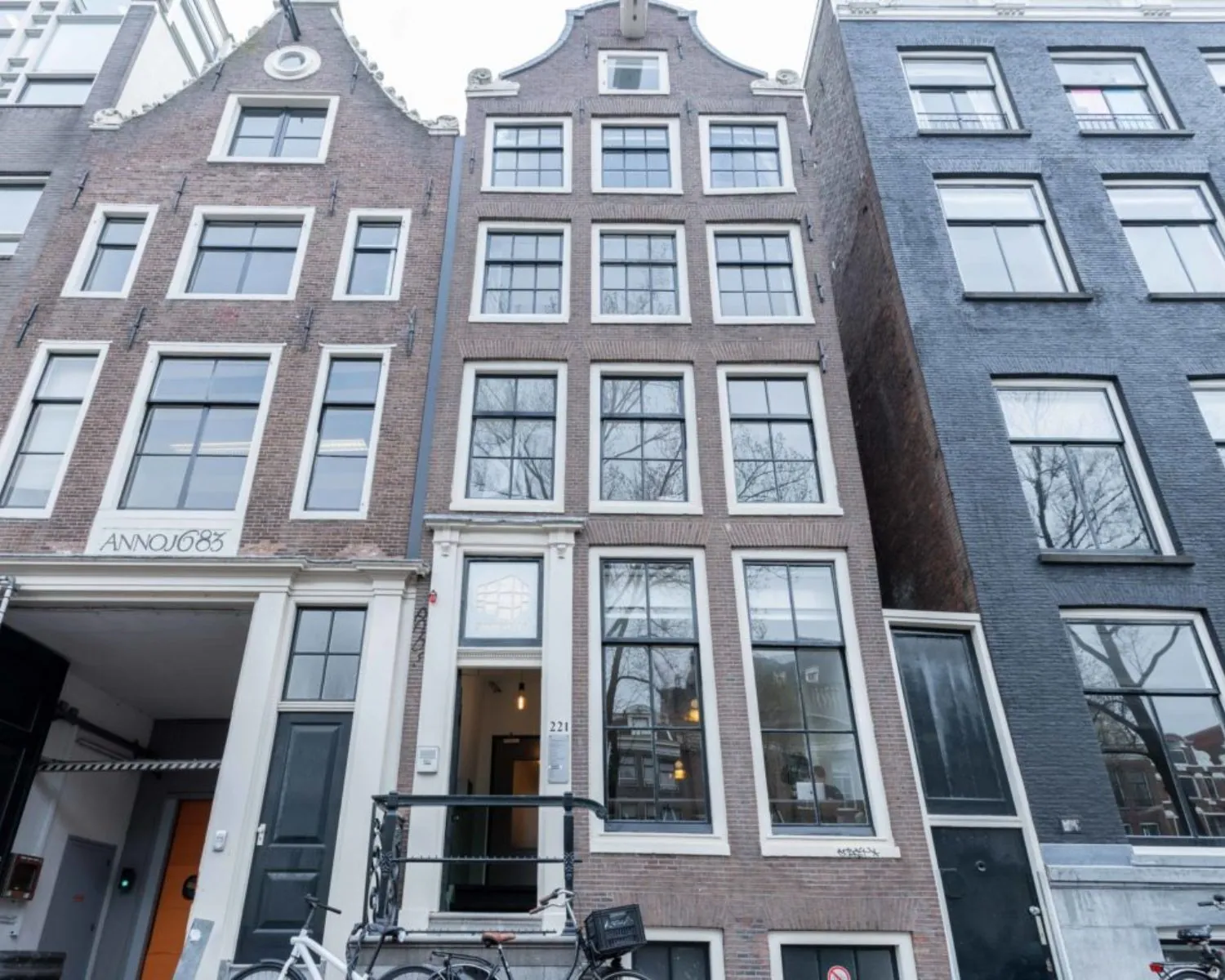 Voorgevel van het historische grachtenpand Herengracht 211 in Amsterdam met hoge ramen en trapgevel.