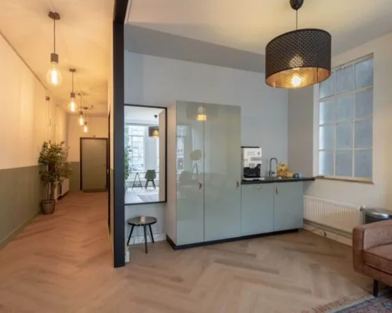 Moderne kantoorruimte aan de Herengracht 211 met een kitchenette, grote raampartij en stijlvolle verlichting.