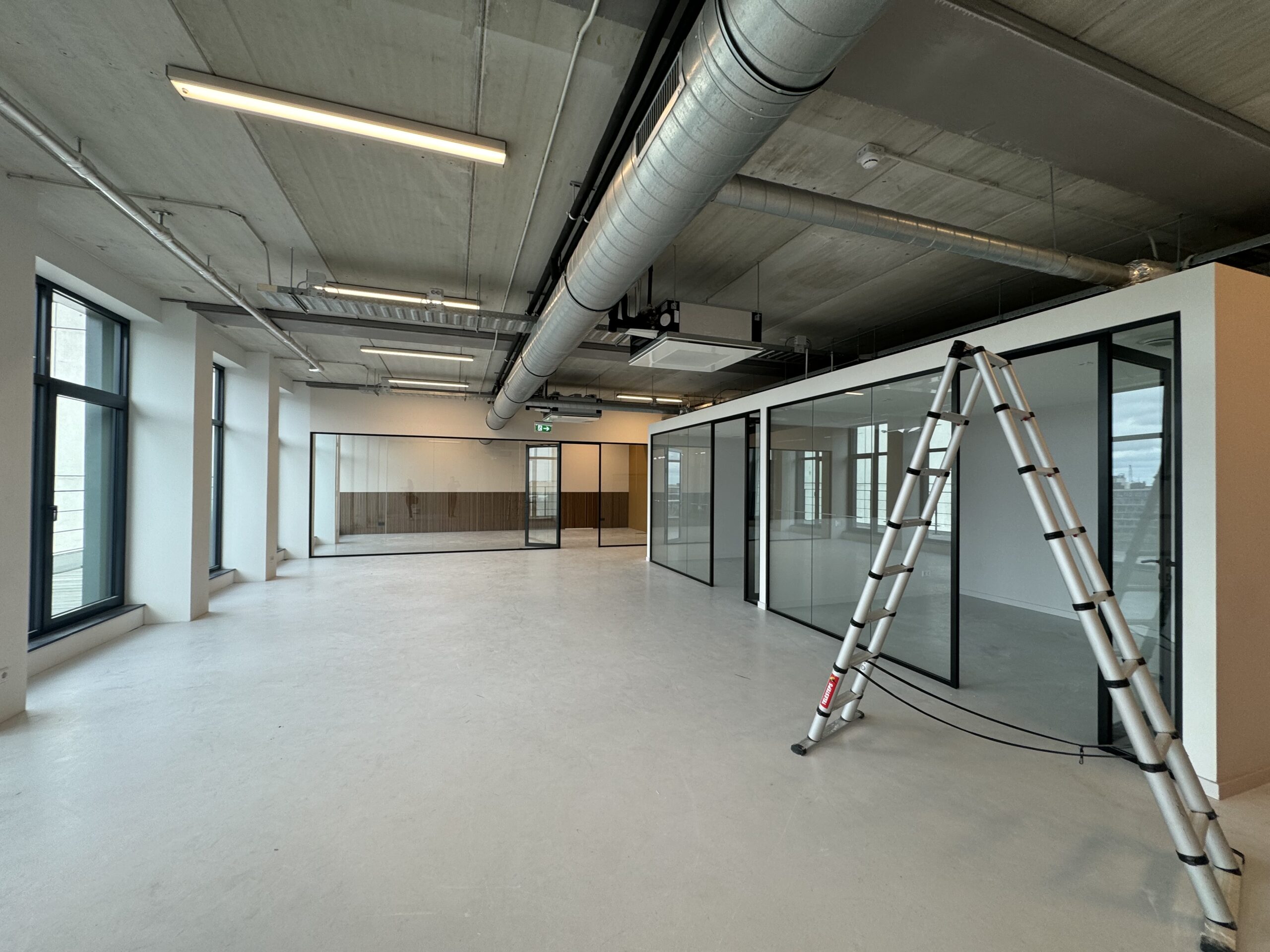 Een leeg, modern kantoor met glazen wanden en een ladder.