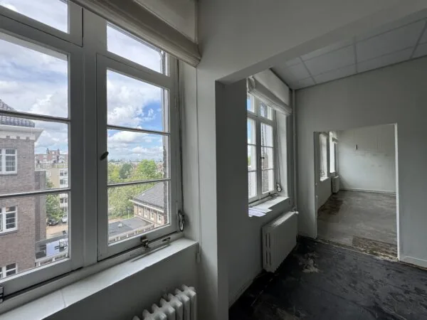 Licht appartement met grote ramen en uitzicht op een stedelijk landschap.