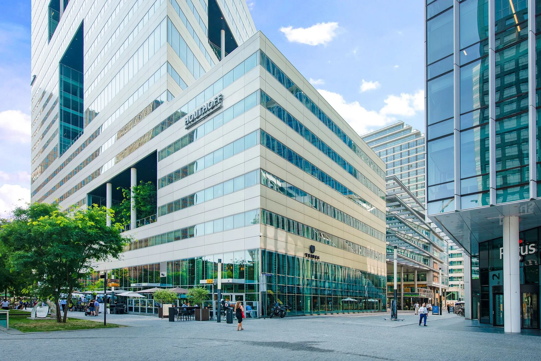 Modern kantoorgebouw Ito met omliggende hoogbouw en bedrijvige straat op de Zuidas in Amsterdam.