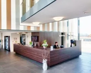 Moderne receptie met houten balie en grote ramen in een kantoorpand te huur boven De Wolfskuil.