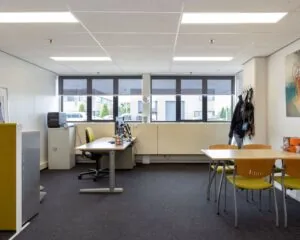 Moderne kantoorruimte aan de Droogdokstraat 1-2 met bureaus, stoelen, vergadertafel en grote ramen.