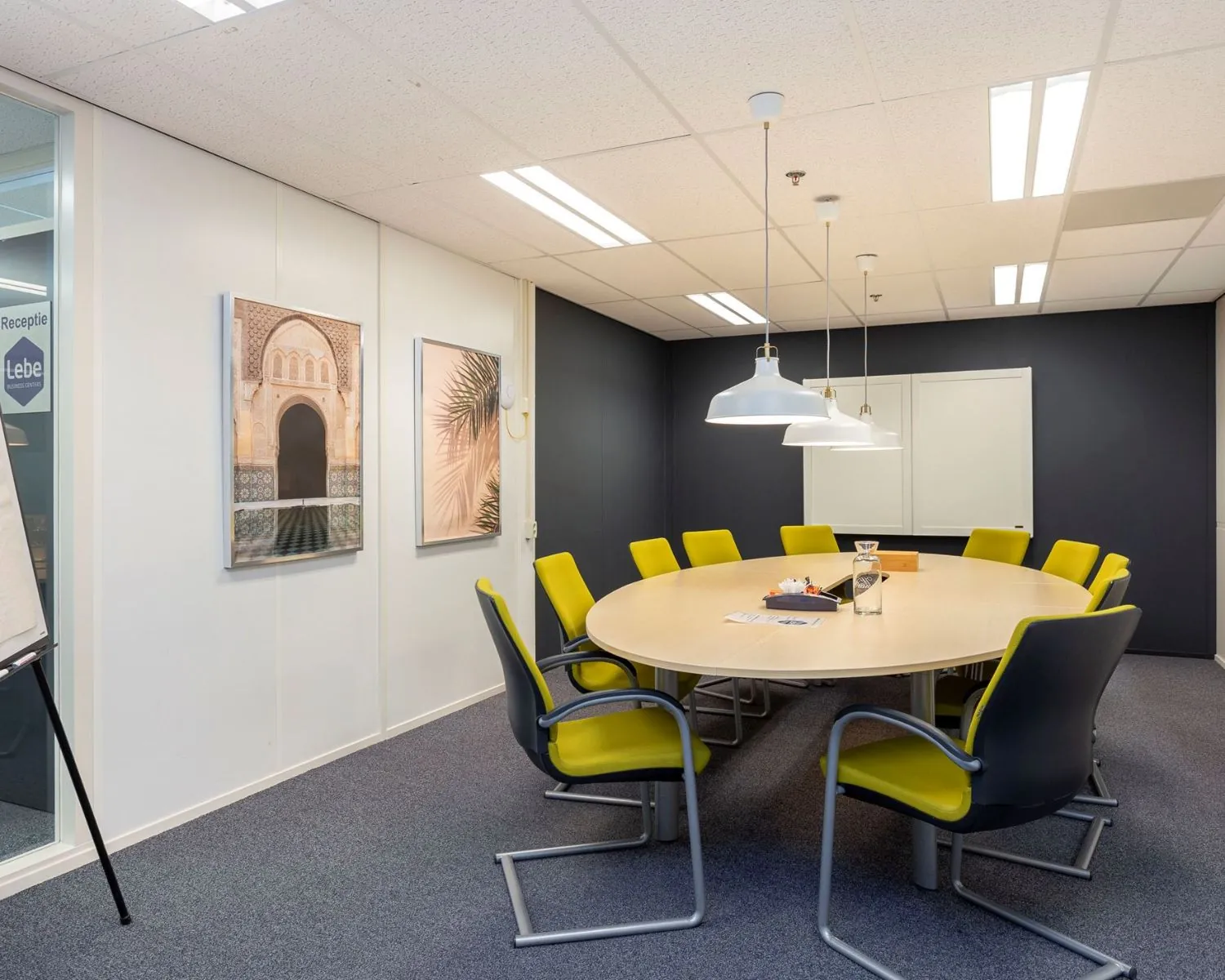 Vergaderruimte met ovale tafel, gele stoelen en moderne verlichting in kantoorruimte aan de Droogdokstraat 1-4.