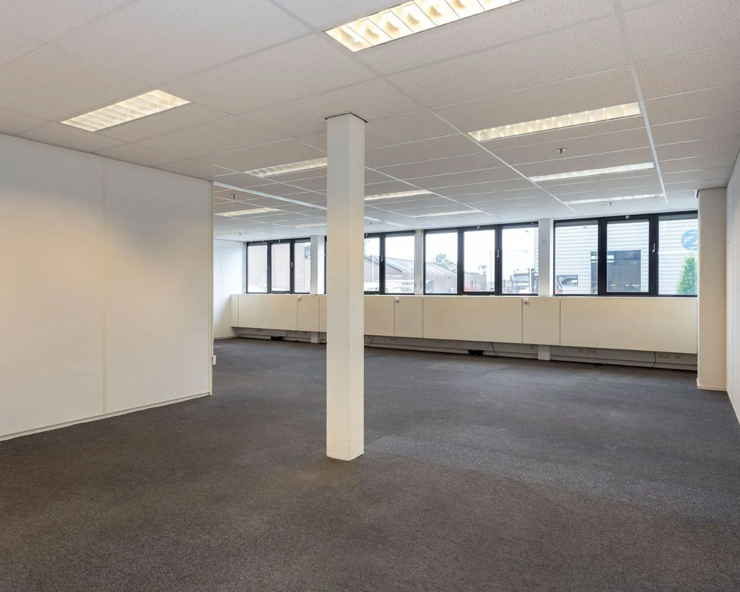 Lichte, open kantoorruimte met systeemplafond en grote ramen aan de Droogdokstraat 1-6.