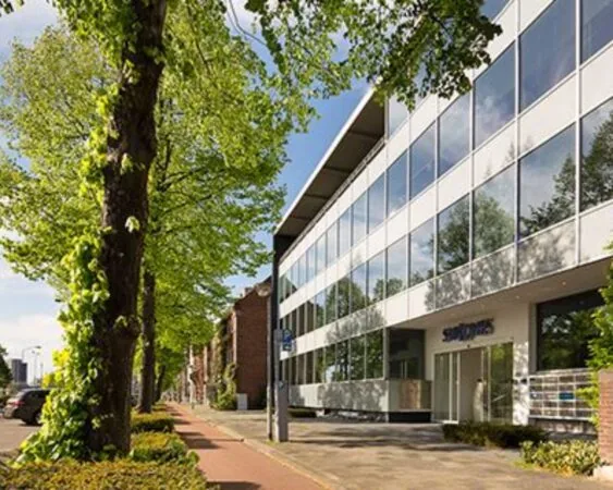 Modern kantoorgebouw aan de Kaldenkerkerweg 20-1 met grote ramen en een groene, boomrijke straat.