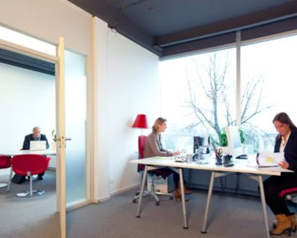 Moderne kantoorruimte aan de Kaldenkerkerweg 20 met meerdere werkplekken en grote ramen.