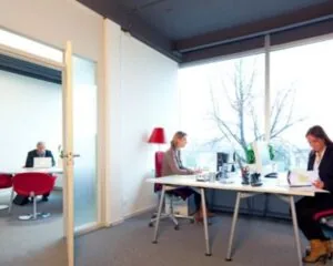 Moderne kantoorruimte aan de Kaldenkerkerweg 20 met meerdere werkplekken en grote ramen.