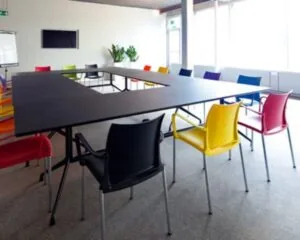 Vergaderruimte met een U-vormige tafel en felgekleurde stoelen aan de Kaldenkerkerweg 20.