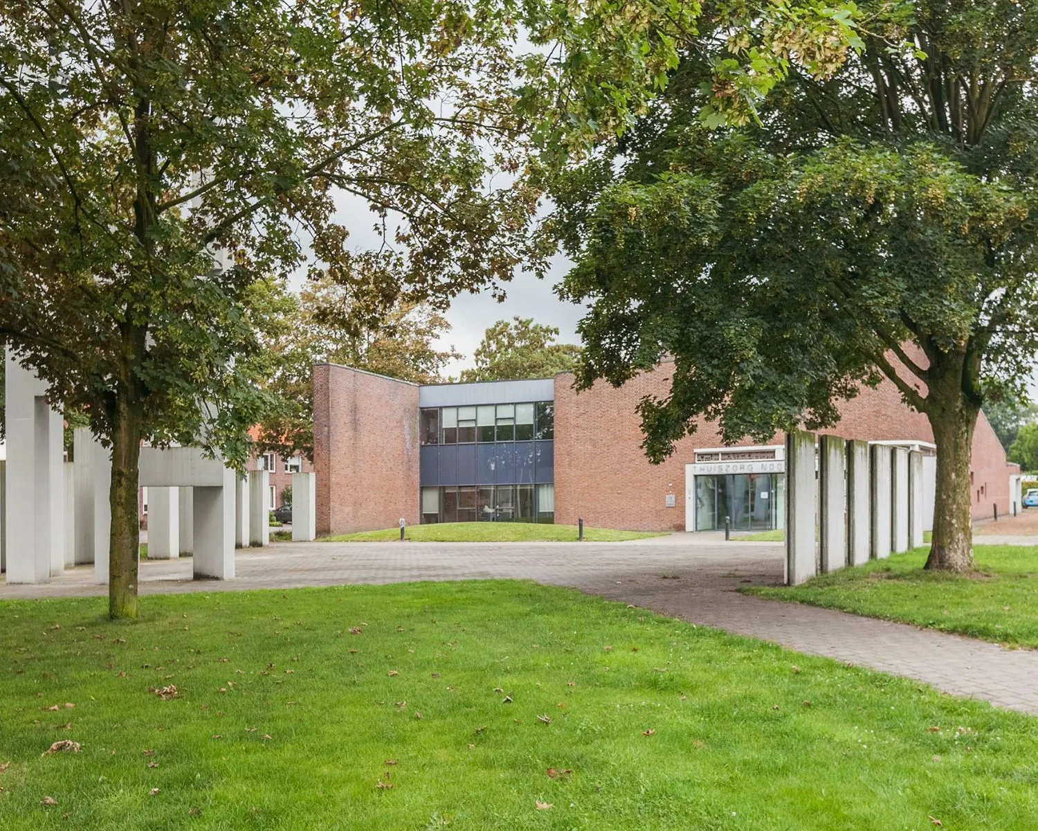 Bakstenen kantoorgebouw aan het Kennedyplein 18 met moderne architectuur, omgeven door bomen en groen.