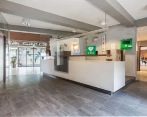 Moderne receptiebalie in een kantoorruimte aan het Kennedyplein 18 met AED-apparaat aan de muur.