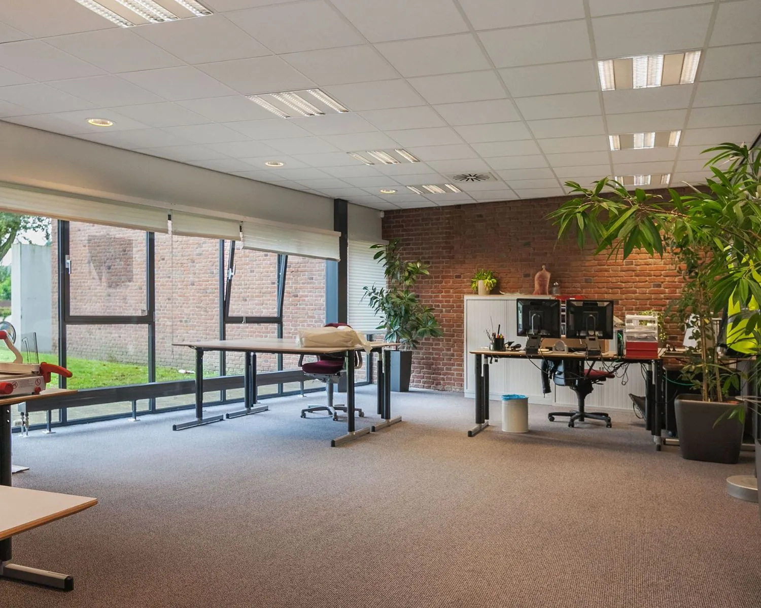 Ruime en moderne kantoorruimte te huur aan het Kennedyplein 18 met grote ramen, bureaus en veel natuurlijk licht.