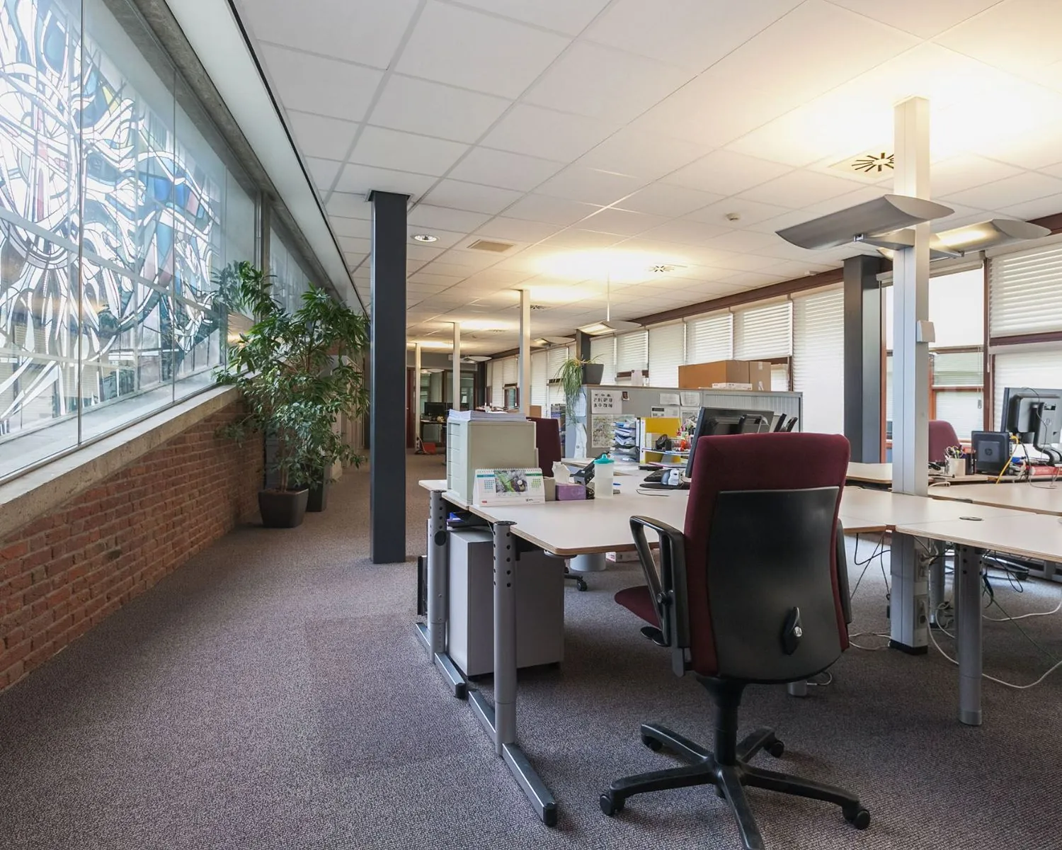 Open kantoorruimte met bureaus en stoelen te huur aan Kennedyplein 18.