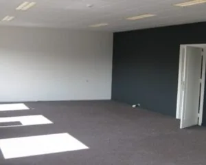 Lege kantoorruimte met grijze muren en donker tapijt aan de Nusterweg 63.