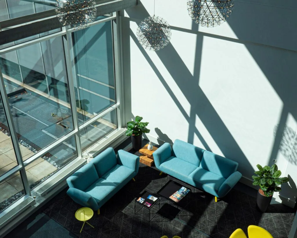 Moderne wachtruimte in kantoorpand Snellius met blauwe banken, grote ramen en veel natuurlijk licht.