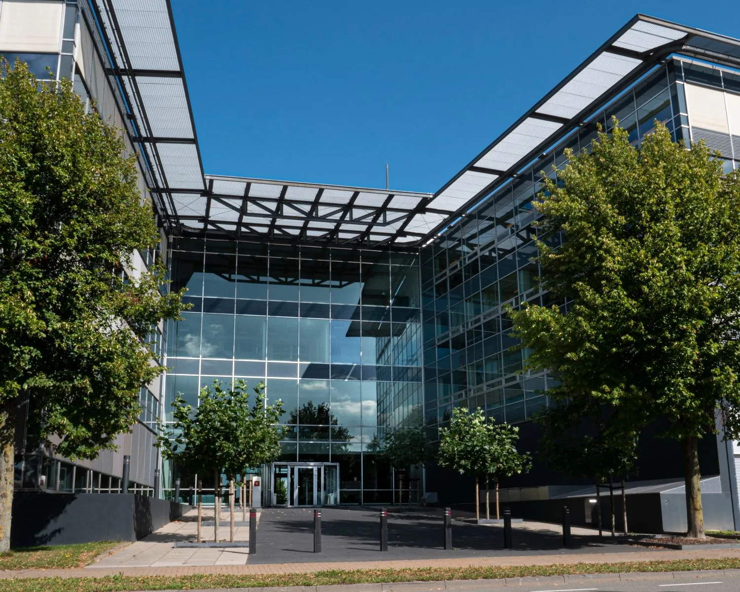 Moderne kantoorgebouw Snellius 1-4 met glazen gevel en entree, omgeven door bomen.