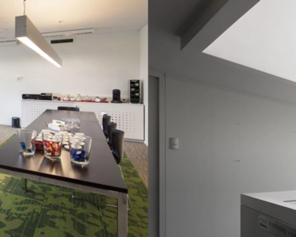 Vergaderruimte met lange tafel, stoelen en koffiecorner in een kantoorruimte aan de Transportlaan 30.