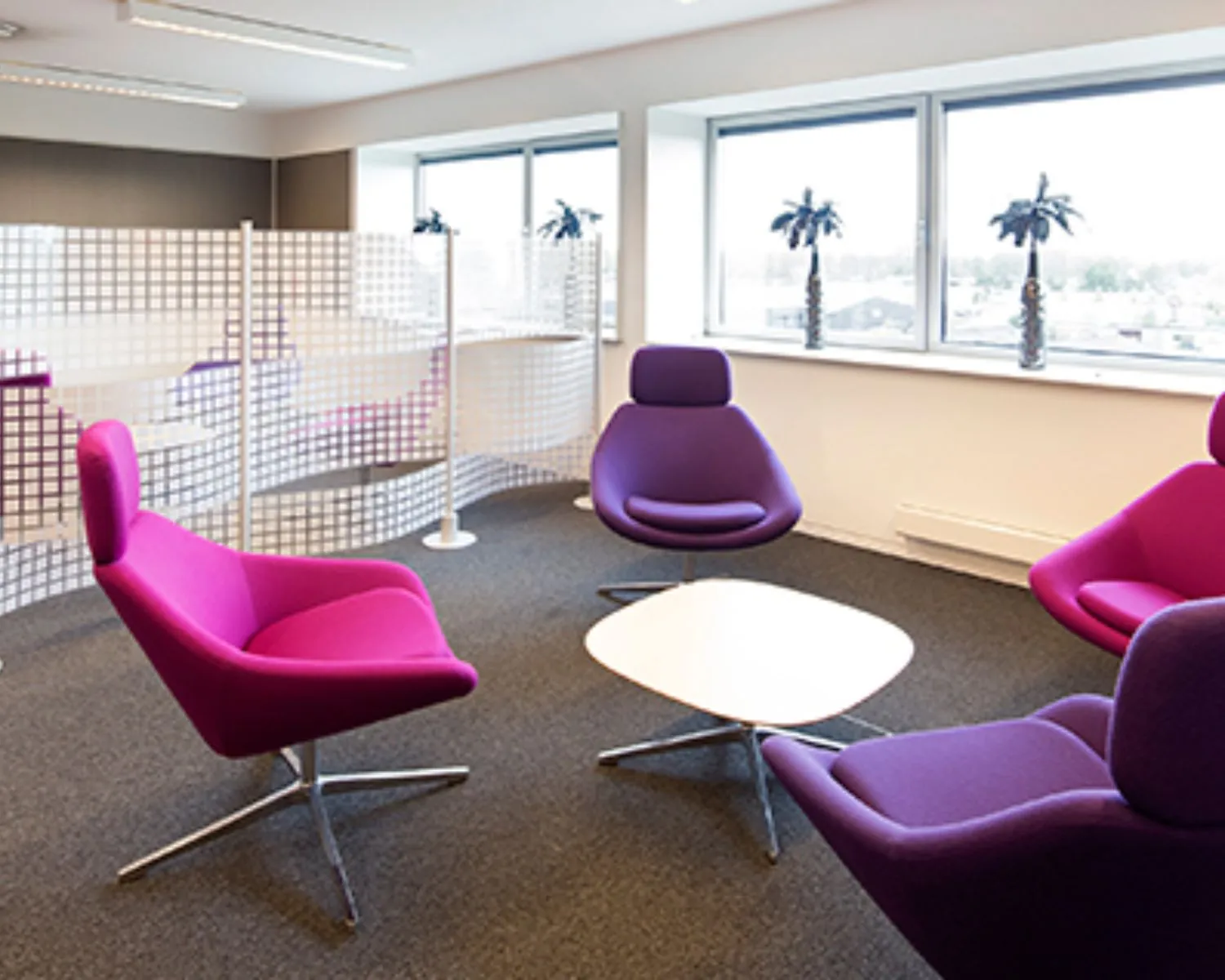 Moderne kantoorruimte aan de Transportlaan 30 met paarse designstoelen, een witte salontafel en grote ramen met uitzicht.