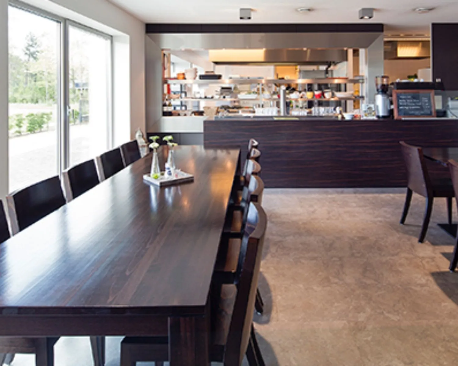 Moderne gemeenschappelijke kantineruimte met grote houten tafel en open keuken in kantoorpand aan de Transportlaan 30.