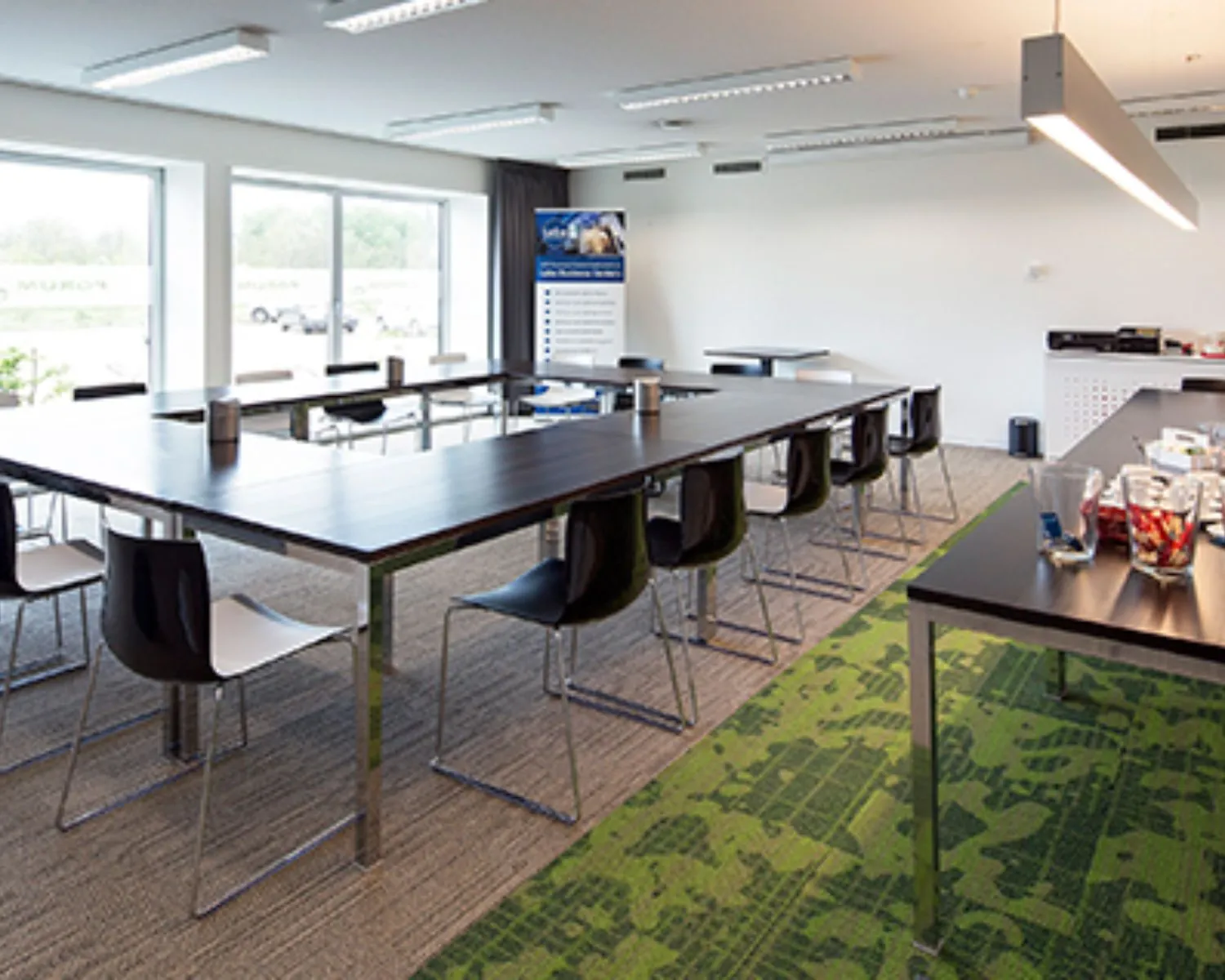 Moderne kantoorruimte aan de Transportlaan 30 met vergadertafels, stoelen en een presentatietafel met snacks en drankjes.