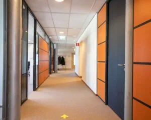 Moderne kantoorruimte aan de Venrayseweg 180 met oranje-houten wanden, glazen kantoordeuren en een nette, lichte gang.