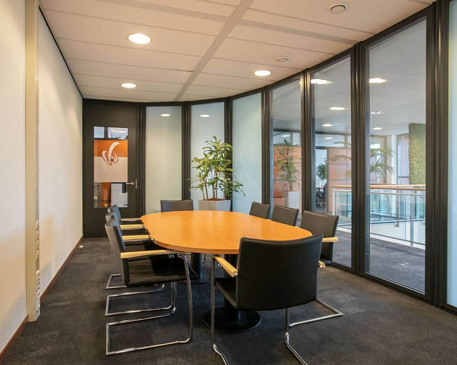 Moderne vergaderruimte met ovale houten tafel en zes stoelen in een kantoor aan de Venrayseweg 180.