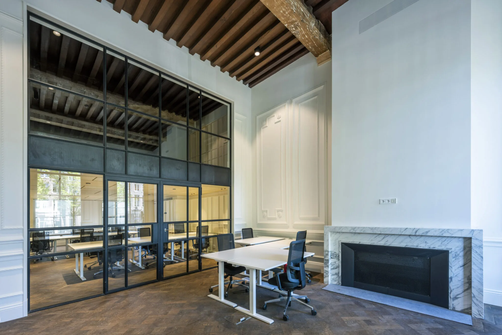 Modern kantoorinterieur met glazen vergaderruimte, houten plafondbalken en een marmeren open haard.