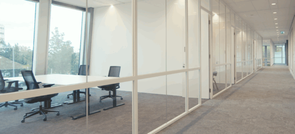 Moderne kantoorruimte met glazen wanden langs een brede, lichte gang.